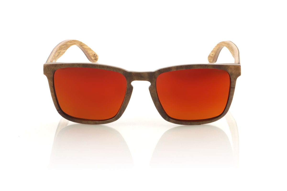 Wood eyewear of Burr OLIVER. OLIVER wooden sunglasses, medium in size and with a square shape with rounded and soft lines, are the perfect balance between design and nature. Made with a careful lamination of olive wood on the outside and interspersed with layers of beech wood, they stand out for the warm color and unique grain that olive wood offers. This combination not only provides exceptional resistance, but also makes each pair a unique piece. With a measurement of 145x47 and a caliber of 53, the OLIVER adapts wonderfully, offering comfort and unmistakable style to those who wear them. Ideal for those looking to stand out with an accessory that speaks of elegance and commitment to the environment. for Wholesale & Retail | Root Sunglasses® 